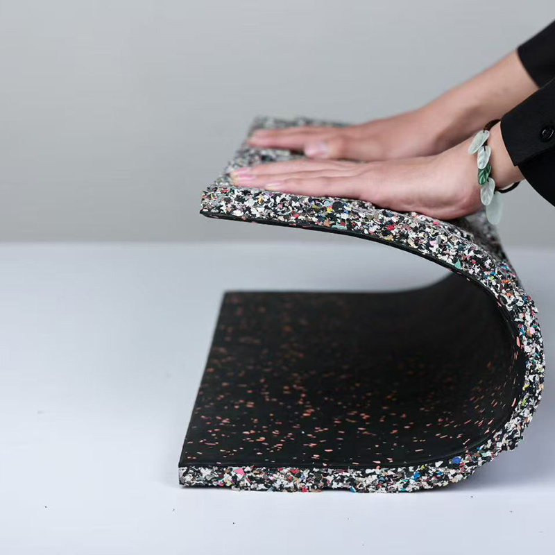 Rubber gym tile demonstrating flexibility and layered construction