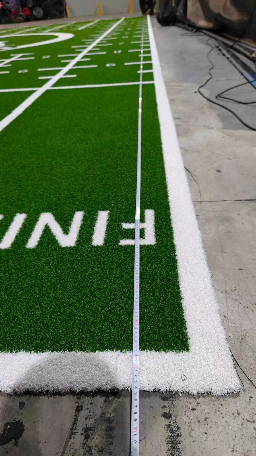 Finished custom green training turf with white numbers and lane graphics during production