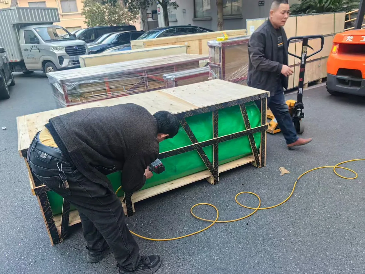 Workers building a custom wooden export crate around the wrapped Netherlands gym turf roll