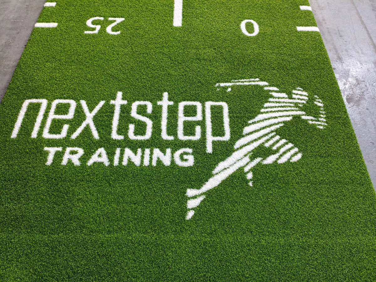 Close view of the woven customer logo on green numbered custom gym turf