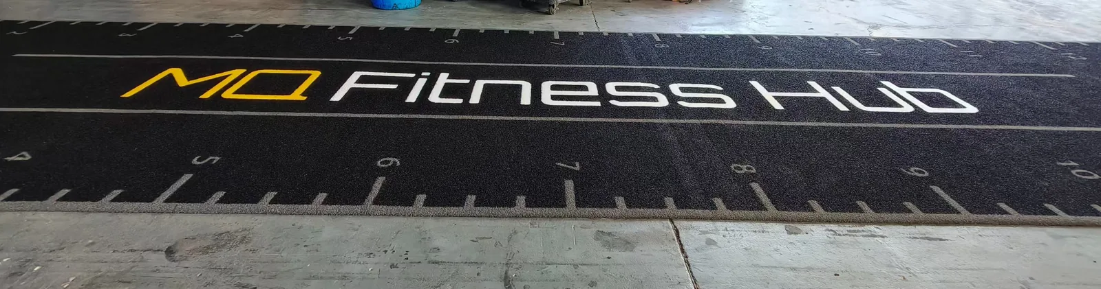 Woven white and yellow gym branding on black functional training turf during factory inspection