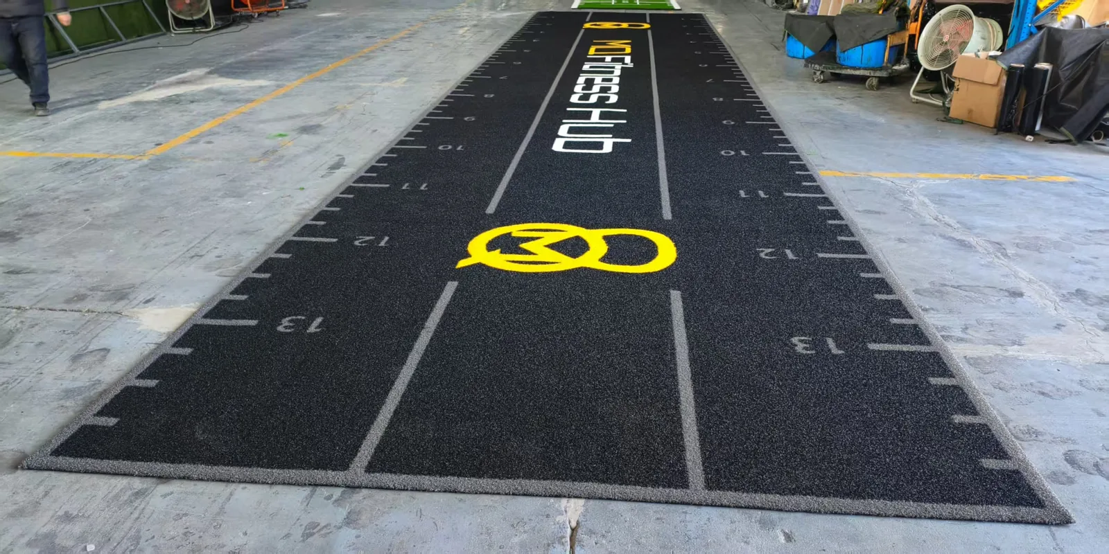 Finished black branded gym turf track laid out for factory inspection before packing