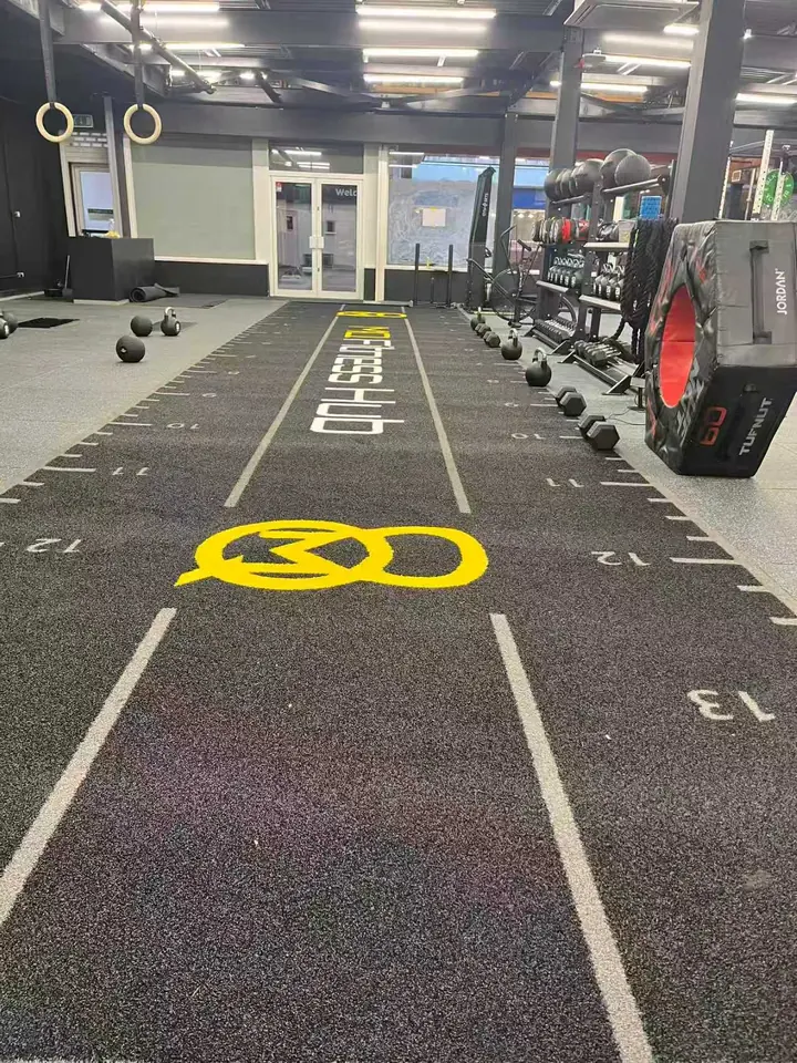 Black 14m by 3m gym turf with yellow woven customer branding installed in a UK gym