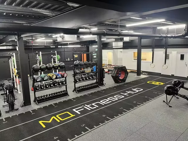 Customer-installed branded black gym turf viewed across a commercial functional fitness area